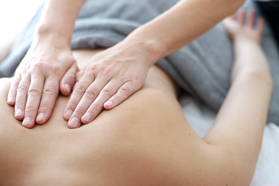 massage therapist working on upper back of client