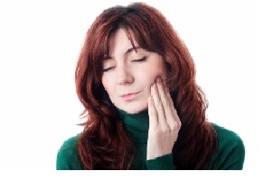 red haired female holding her hand to her painfull jaw, she looks like she needs some tmj treatment